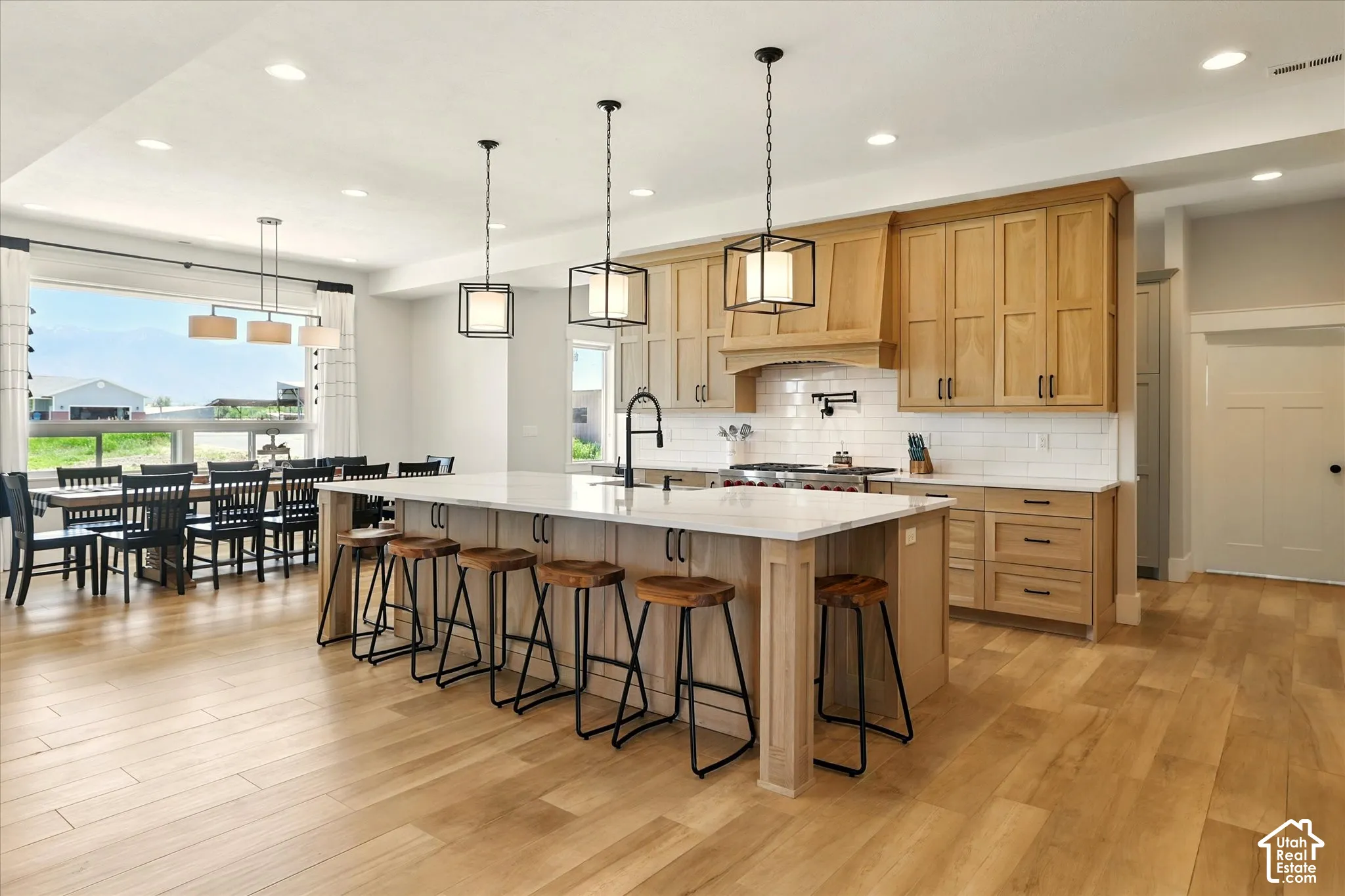 Kitchen featuring natural wood-finish cabinetry, a large central island with quartz countertops, subway tile backsplash, matte black hardware, and recessed lighting