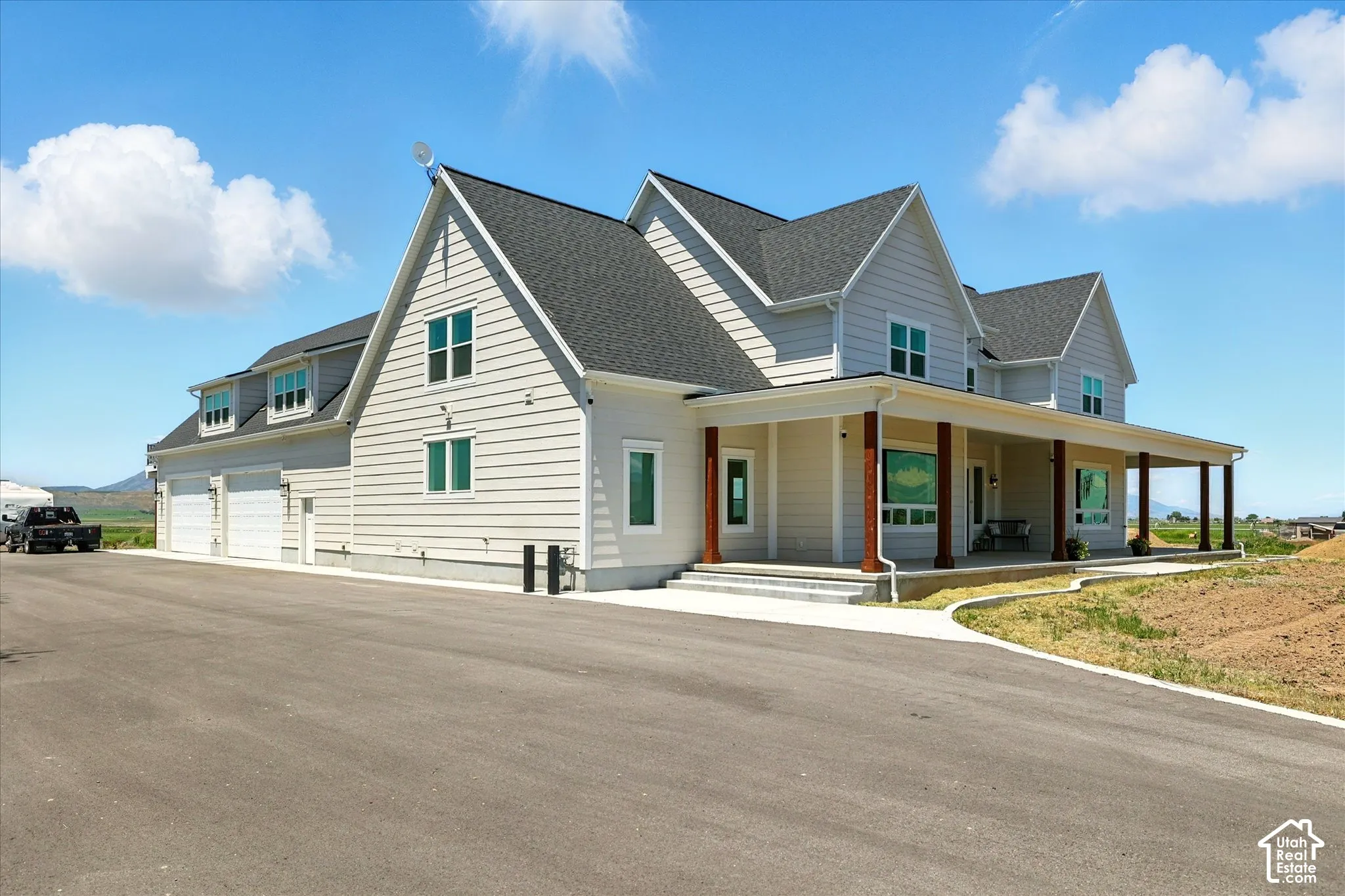 Multi-gabled exterior featuring horizontal lap siding, a wrap-around porch with stained wood columns, multiple dormer windows, and an attached multi-car garage (oversized 4+ car)