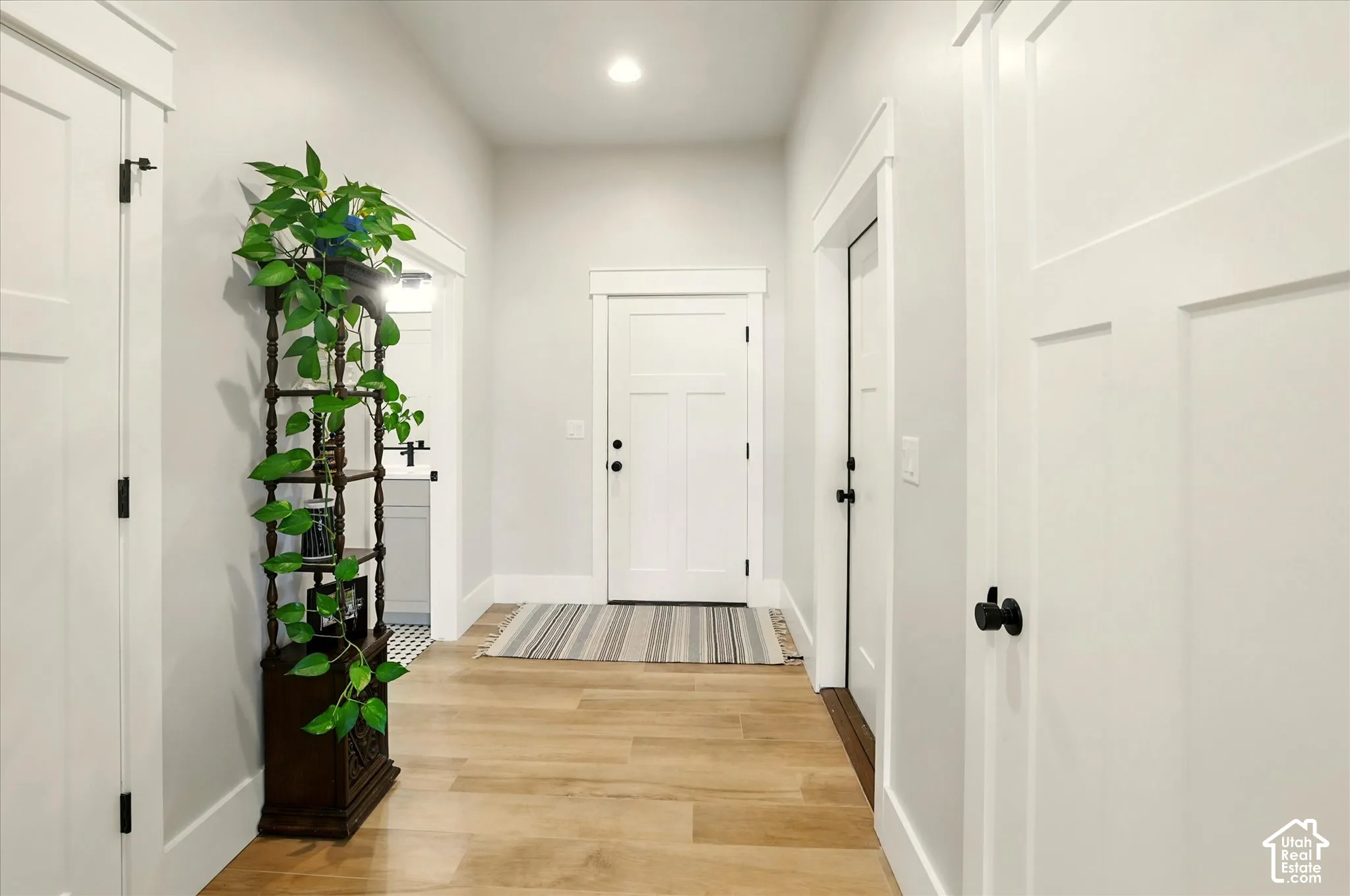 Entryway from garage featuring wood-finish flooring, shaker-style interior doors, recessed lighting, and craftsman-style door casings with header trim