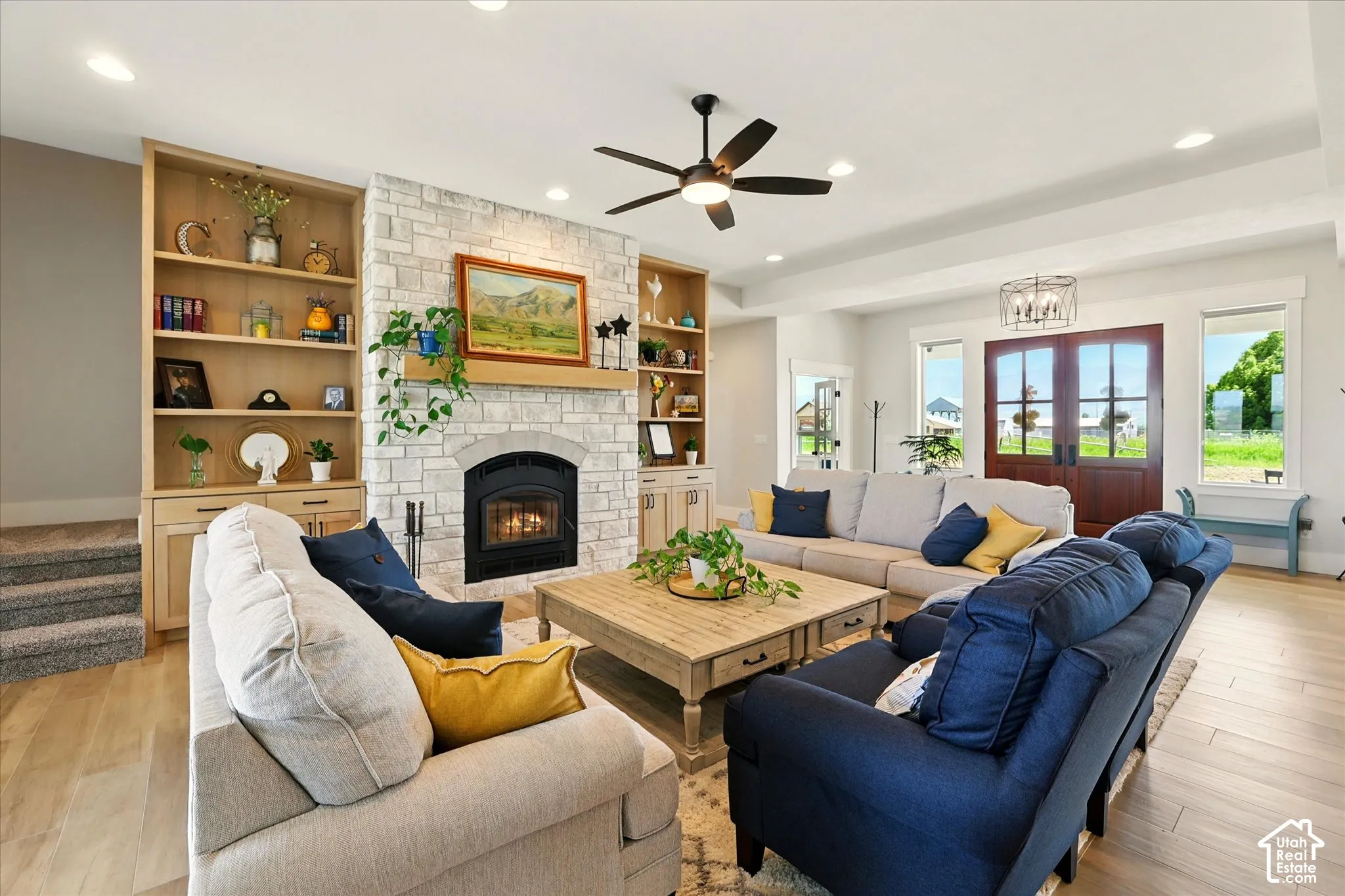 Living area featuring stone-clad fireplace, floor-to-ceiling custom wood shelving, wood-finish tile flooring, recessed lighting, and double-entry wood doors