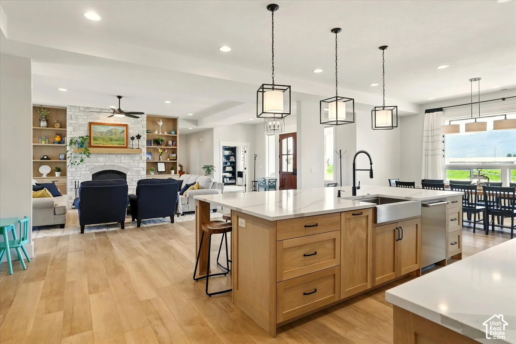 Kitchen featuring a large island with stone countertops, a farmhouse-style sink, and light wood cabinetry