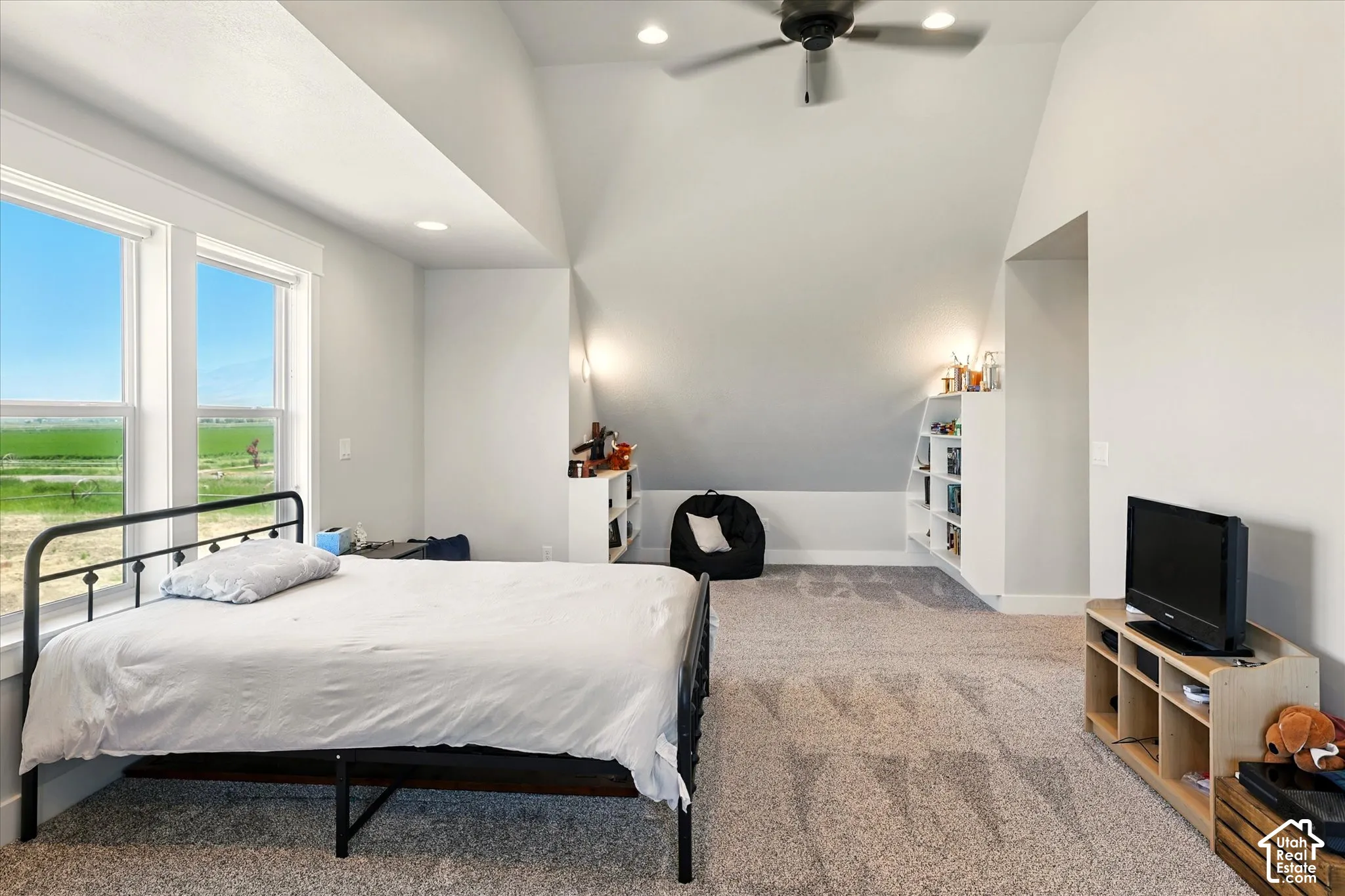 Vaulted ceilings, built-in shelving, carpeted flooring, large windows, and a ceiling fan