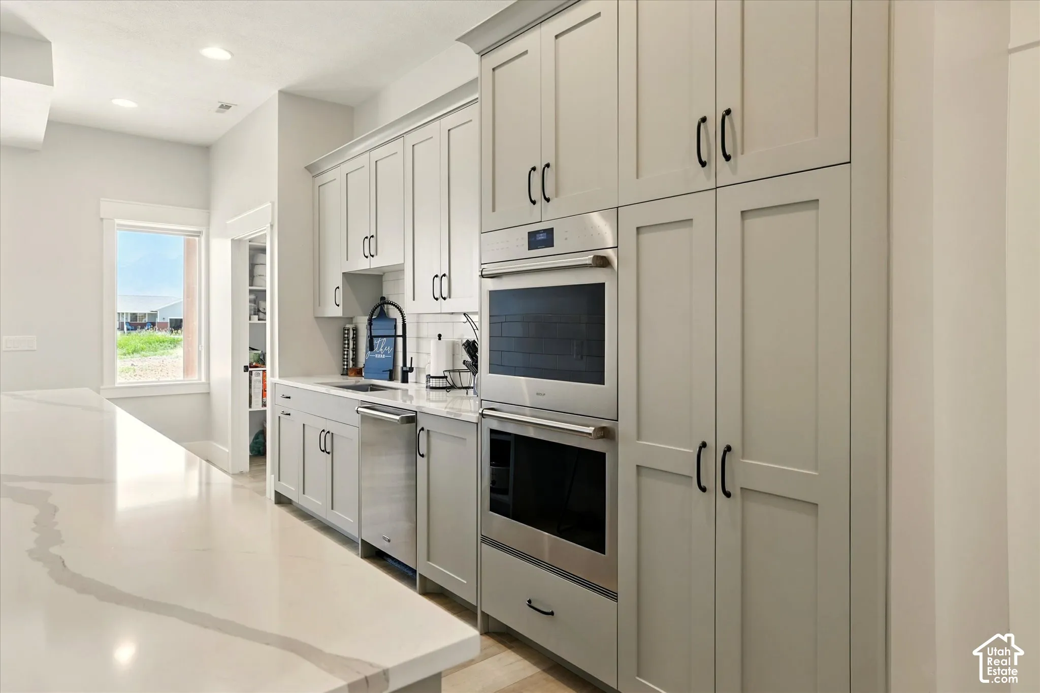 Prep-Kitchen featuring full-height shaker cabinetry, quartz countertops, built-in stainless steel Wolf double ovens, integrated dishwasher, and recessed lighting