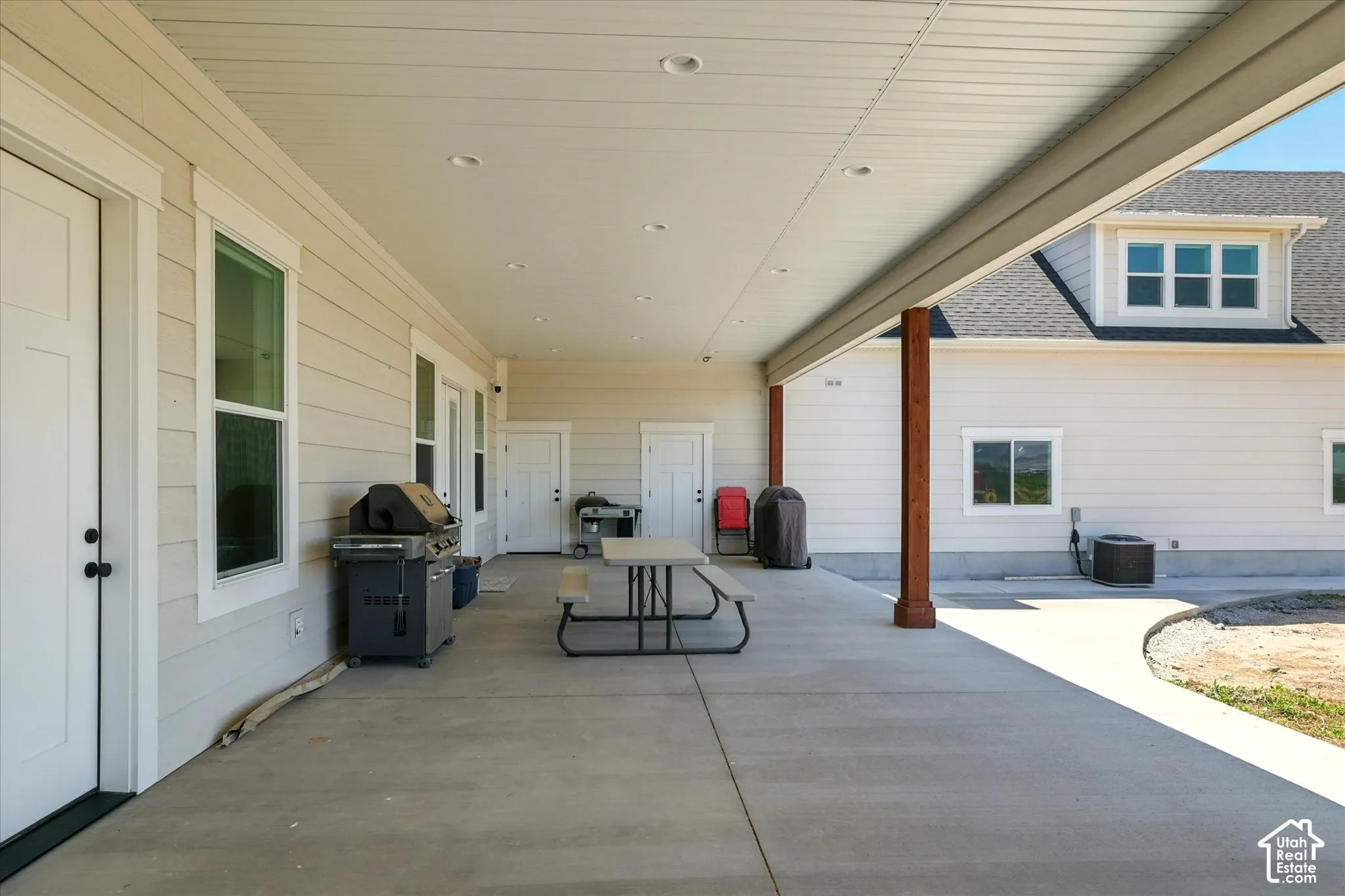 Expansive covered concrete patio featuring recessed ceiling lighting and exposed structural support pillars