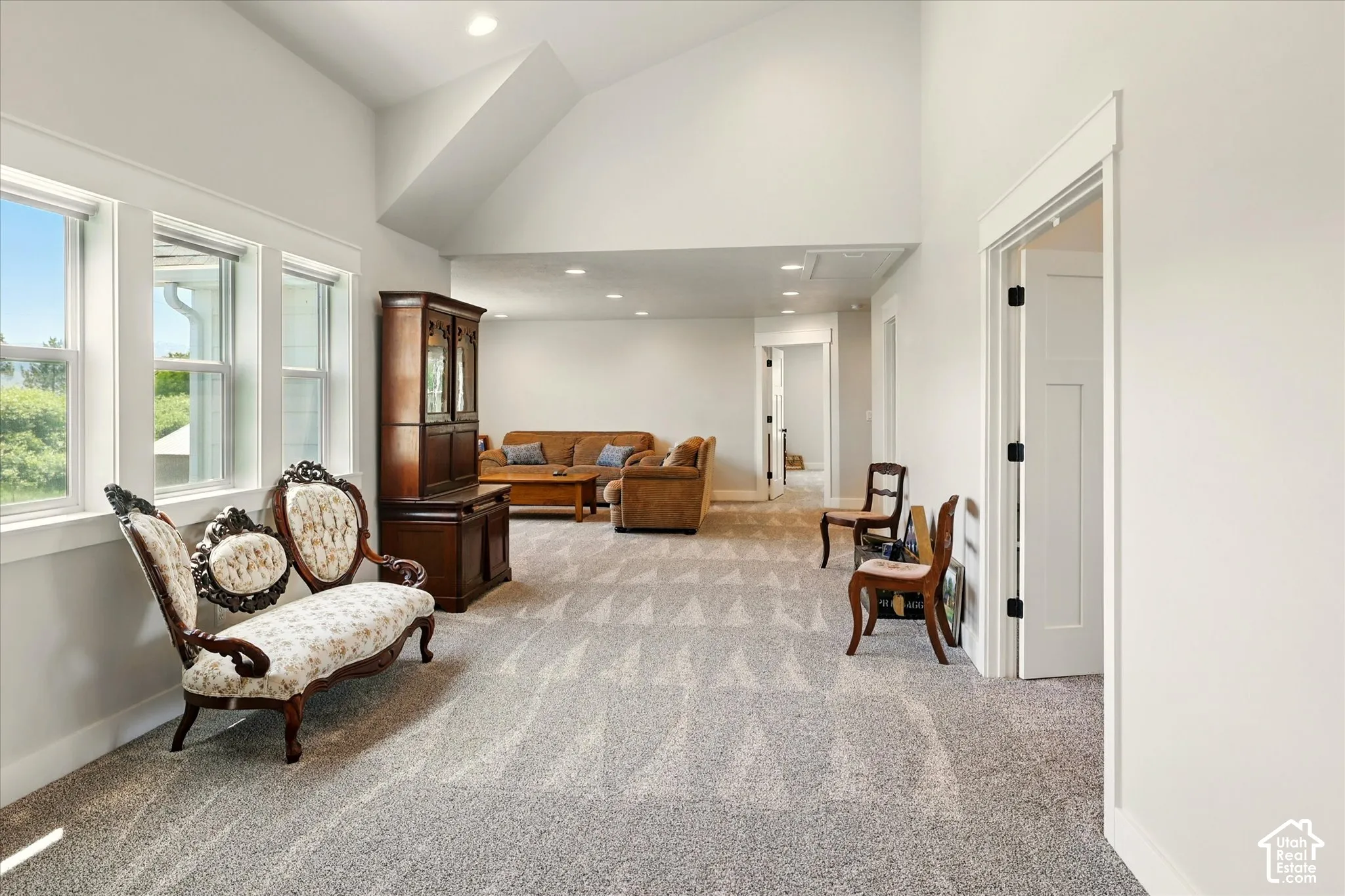 Vaulted ceilings featuring recessed lighting, neutral carpeting, and multi-pane windows with decorative casing