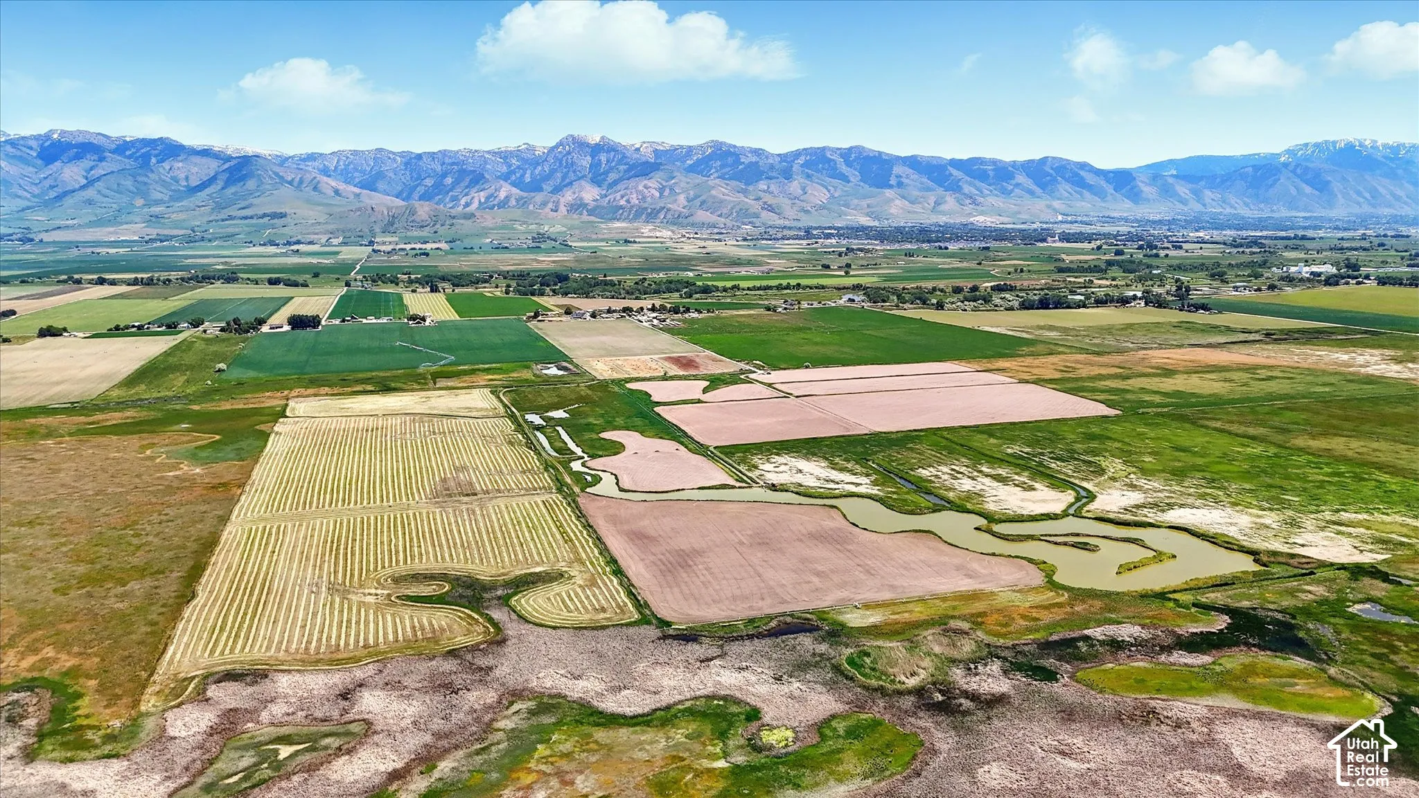Expansive acreage featuring natural water channels, open fields, and a prominent mountain range backdrop