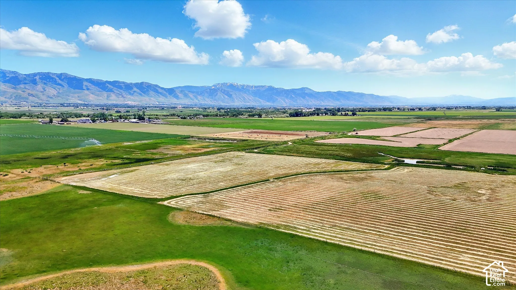 Expansive acreage featuring irrigated agricultural fields and prominent mountain range backdrop