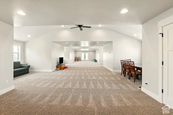 Open-concept bonus room featuring vaulted ceilings, recessed lighting, carpeted flooring, a ceiling fan, and double glass-panel doors leading onto upper deck