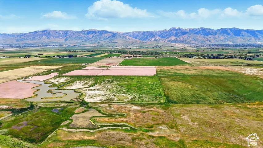 Expansive acreage featuring open pasture land, natural water features, and prominent mountain backdrops