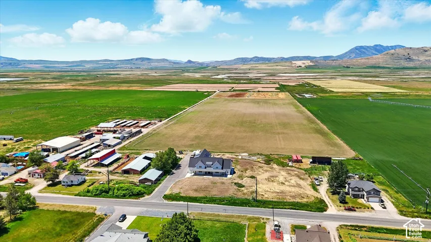 Aerial perspective of extensive acreage featuring multiple outbuildings, open pasture land, and mountain range scenery