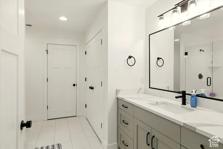 Vanity with stone-finish countertop and integrated sink, matte black hardware, framed vanity mirror, and tile flooring