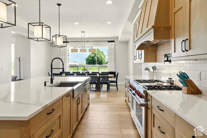 Kitchen featuring wood-finish cabinetry, quartz countertops, a farmhouse-style sink with a matte black faucet, and a professional-grade Wolf gas range with a custom range hood