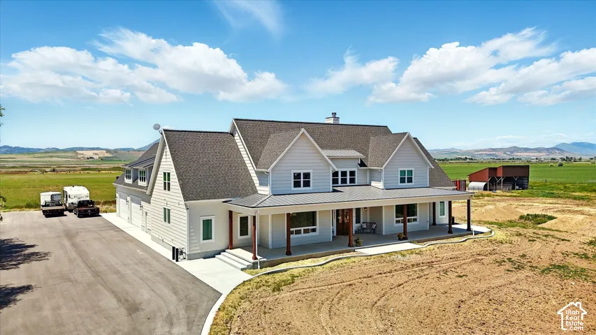Two-story residence featuring horizontal siding, a covered front porch with timber-style pillars, a multi-gabled asphalt shingle roof, and a large paved driveway