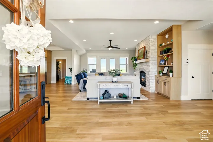 Open-concept interior featuring wood-finish tile flooring, a stone-faced fireplace with a wood mantel, built-in cabinetry, and recessed lighting