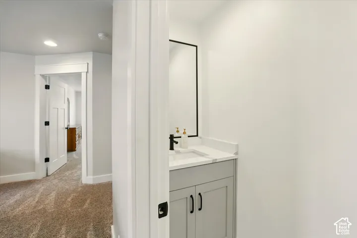 Shaker-style vanity with a stone countertop, rectangular undermount sink, matte black faucet, and matching framed mirror