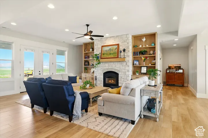 Living area featuring wood-finish tile flooring, a stone-surround fireplace with a wooden mantel, and custom built-in shelving