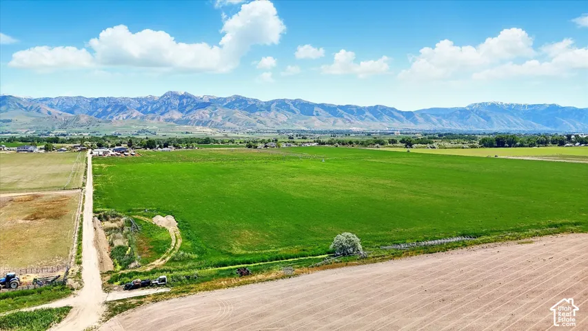 Expansive acreage featuring open green space, dirt road access, and prominent mountain backdrops