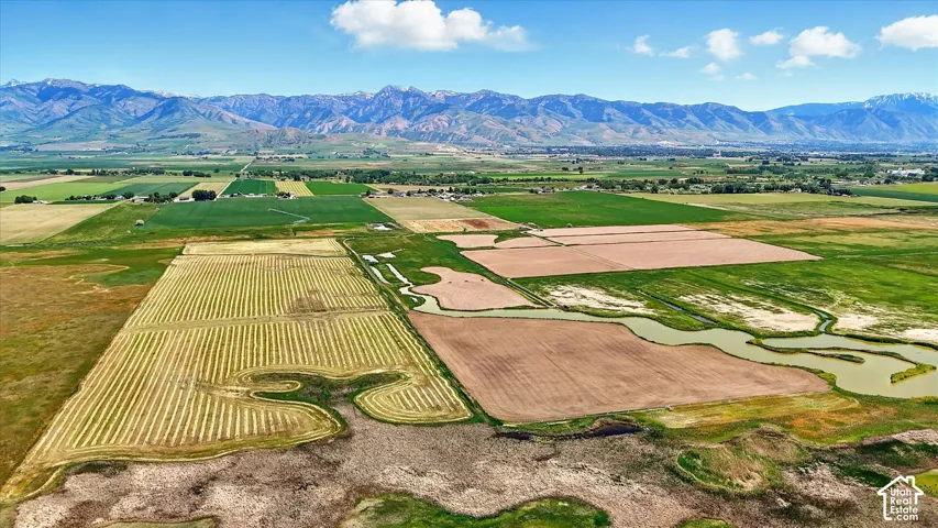 Expansive agricultural acreage featuring vast cultivated fields, natural waterways, and a prominent mountain backdrop