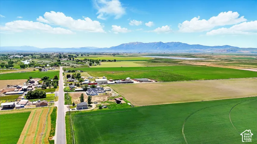 Expansive acreage featuring open fields, paved road access, and mountain range backdrop