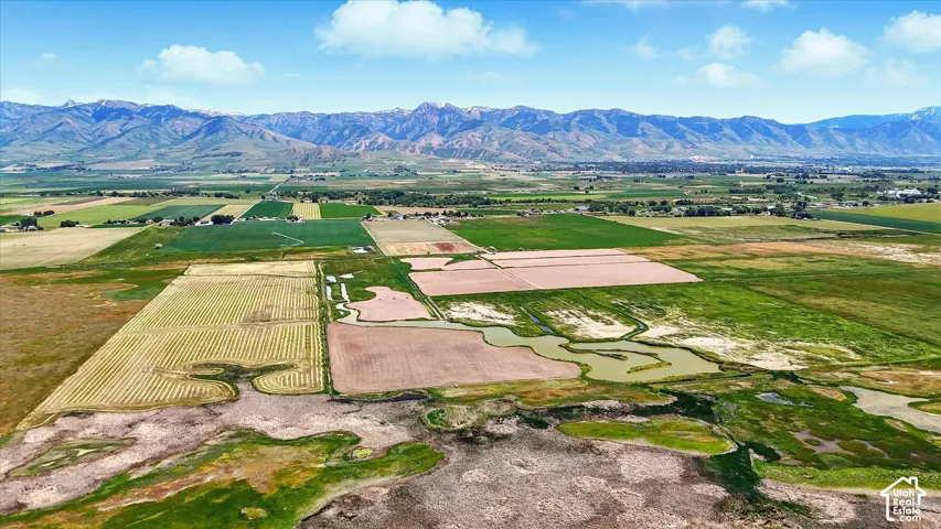 Expansive acreage featuring cultivated fields, natural marshland, winding waterways, and a prominent mountain range backdrop