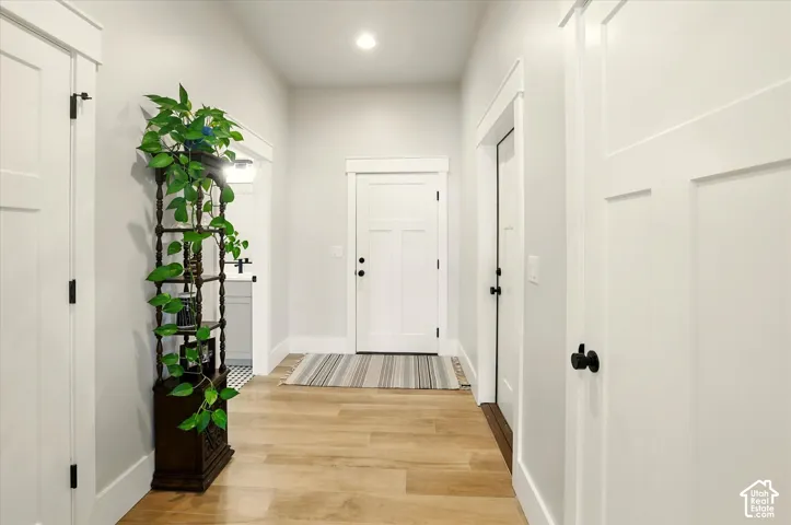 Entryway from garage featuring wood-finish flooring, shaker-style interior doors, recessed lighting, and craftsman-style door casings with header trim