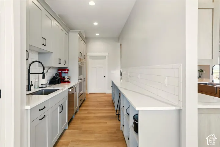 Prep-Kitchen featuring light grey Shaker cabinetry, white quartz countertops, white subway tile backsplash, matte black hardware, and wood-finish flooring
