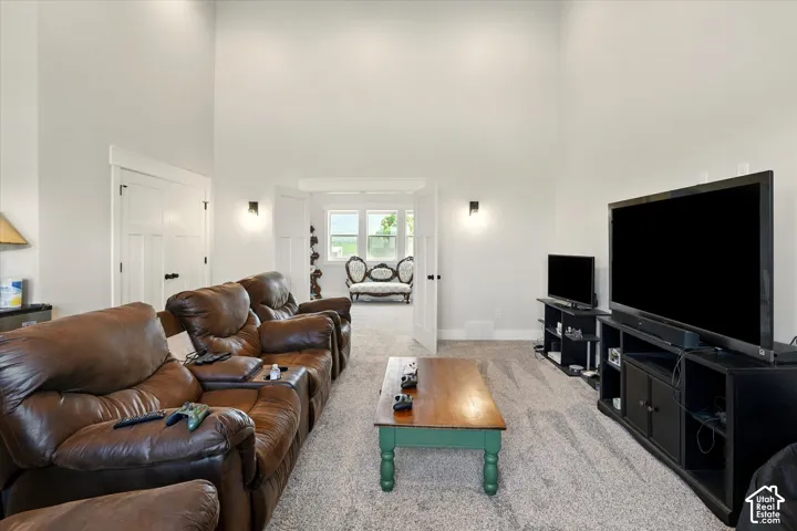 Expansive room featuring vaulted ceilings, neutral wall color, carpeting, and double-door entry