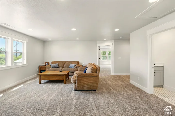Neutral-toned interior space featuring recessed ceiling lighting, wall-to-wall carpeting, multiple windows, and a separate room entrance in half bath