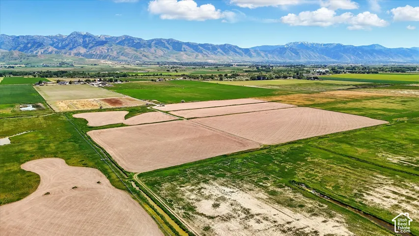 Expansive acreage featuring cultivated fields, open meadows, and a mountain backdrop