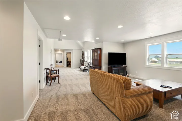 Open-concept living space featuring vaulted ceilings, recessed lighting, neutral wall tones, and large dual-pane windows