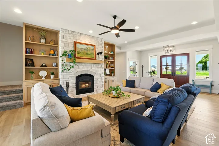 Living area featuring stone-clad fireplace, floor-to-ceiling custom wood shelving, wood-finish tile flooring, recessed lighting, and double-entry wood doors
