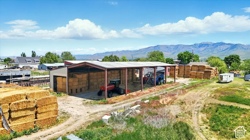 Open-sided pole barn featuring a metal roof, steel support beams, and mountain scenery