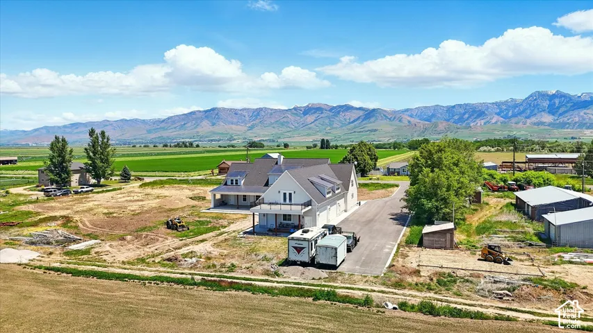 Multi-level residence featuring a covered deck, attached garage, expansive acreage, and mountainous scenery