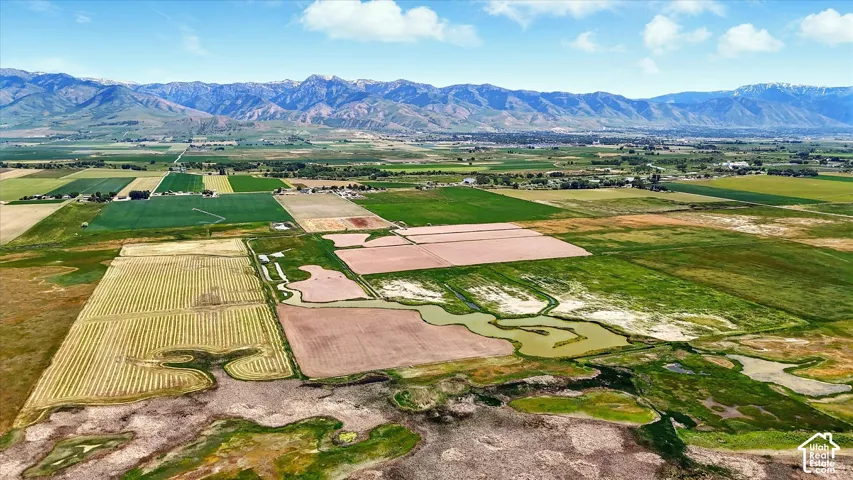 Expansive acreage featuring sprawling open fields, natural waterways, and a prominent mountain range backdrop