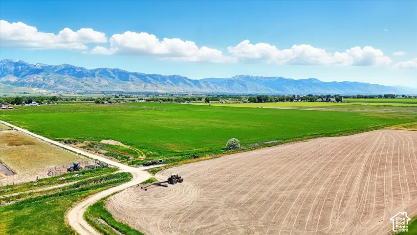Expansive acreage featuring cultivated fields, unpaved paths, and mountain scenery