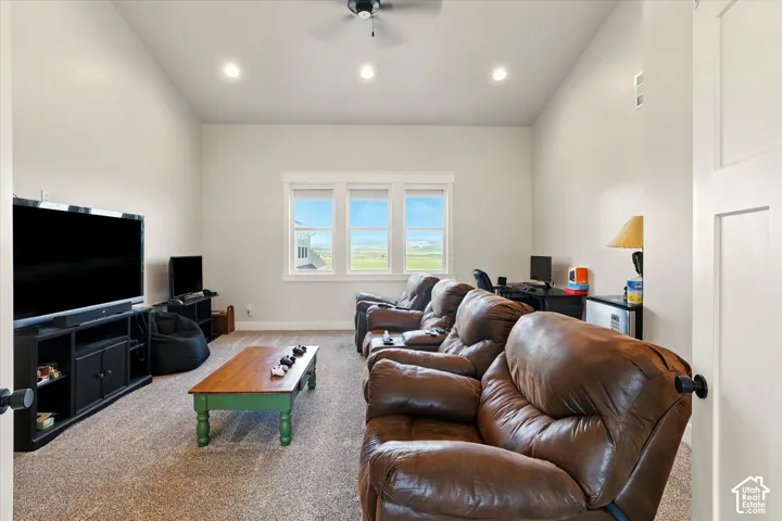 Vaulted ceilings, recessed lighting, carpeted flooring, and a bank of three windows featuring exterior mountain scenery