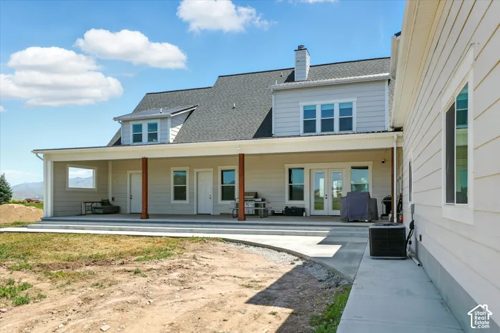 Exterior featuring a wide covered patio with wooden support posts, light-toned horizontal siding, and multiple double-hung windows