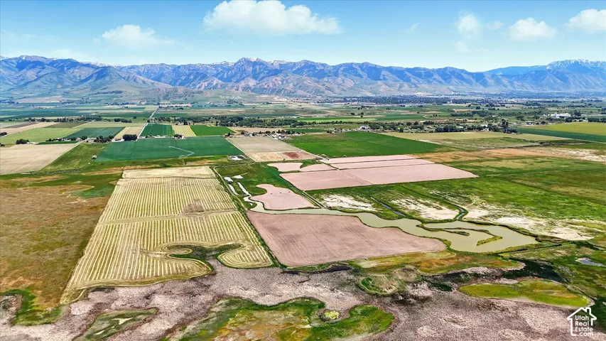 Expansive acreage featuring natural water channels, open fields, and a prominent mountain range backdrop