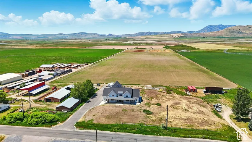 Expansive acreage featuring multiple outbuildings, agricultural fields, a paved driveway, and mountain topography