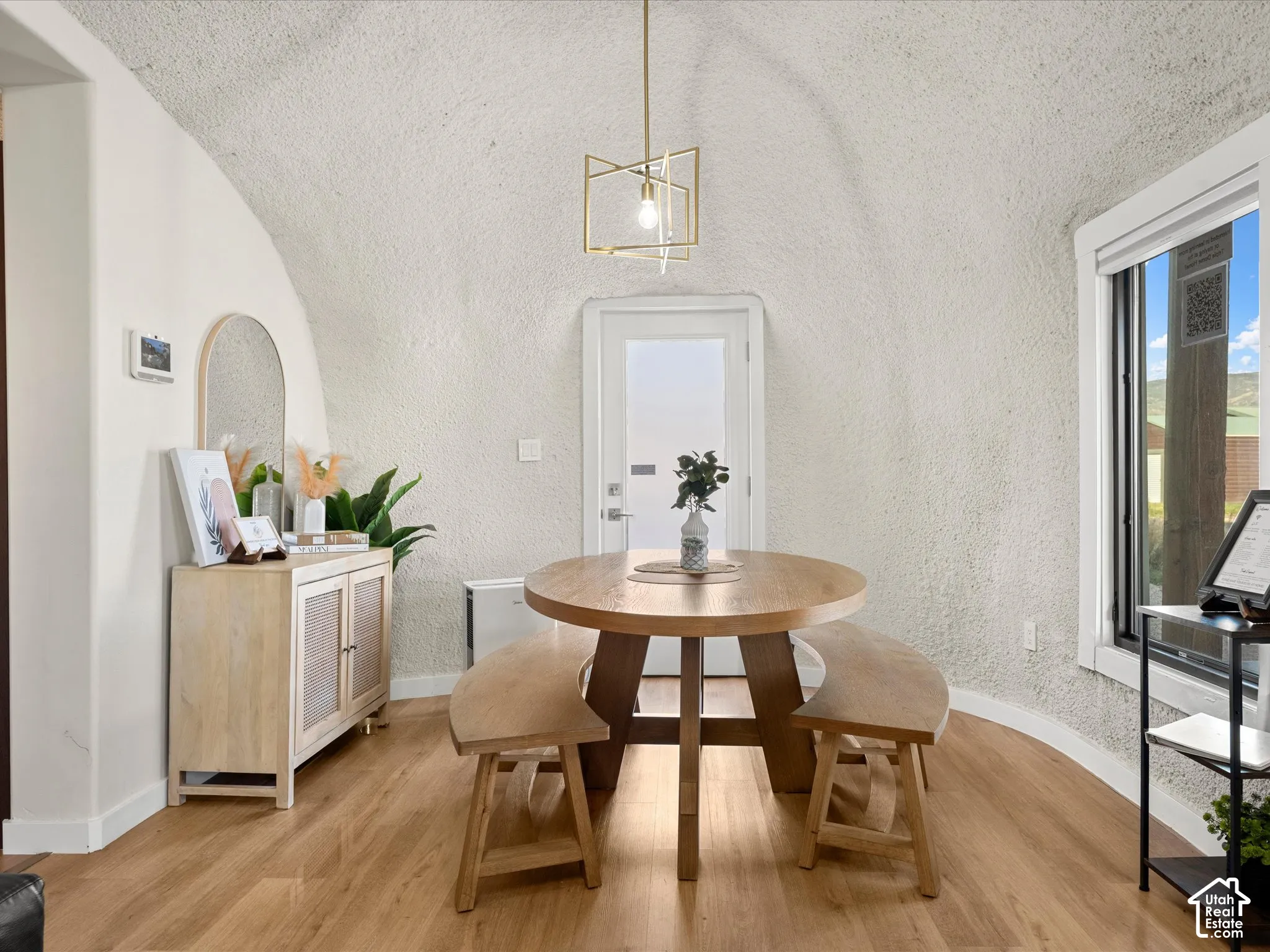 Vaulted architectural ceiling with textured finish, wood-finish flooring, and geometric pendant lighting