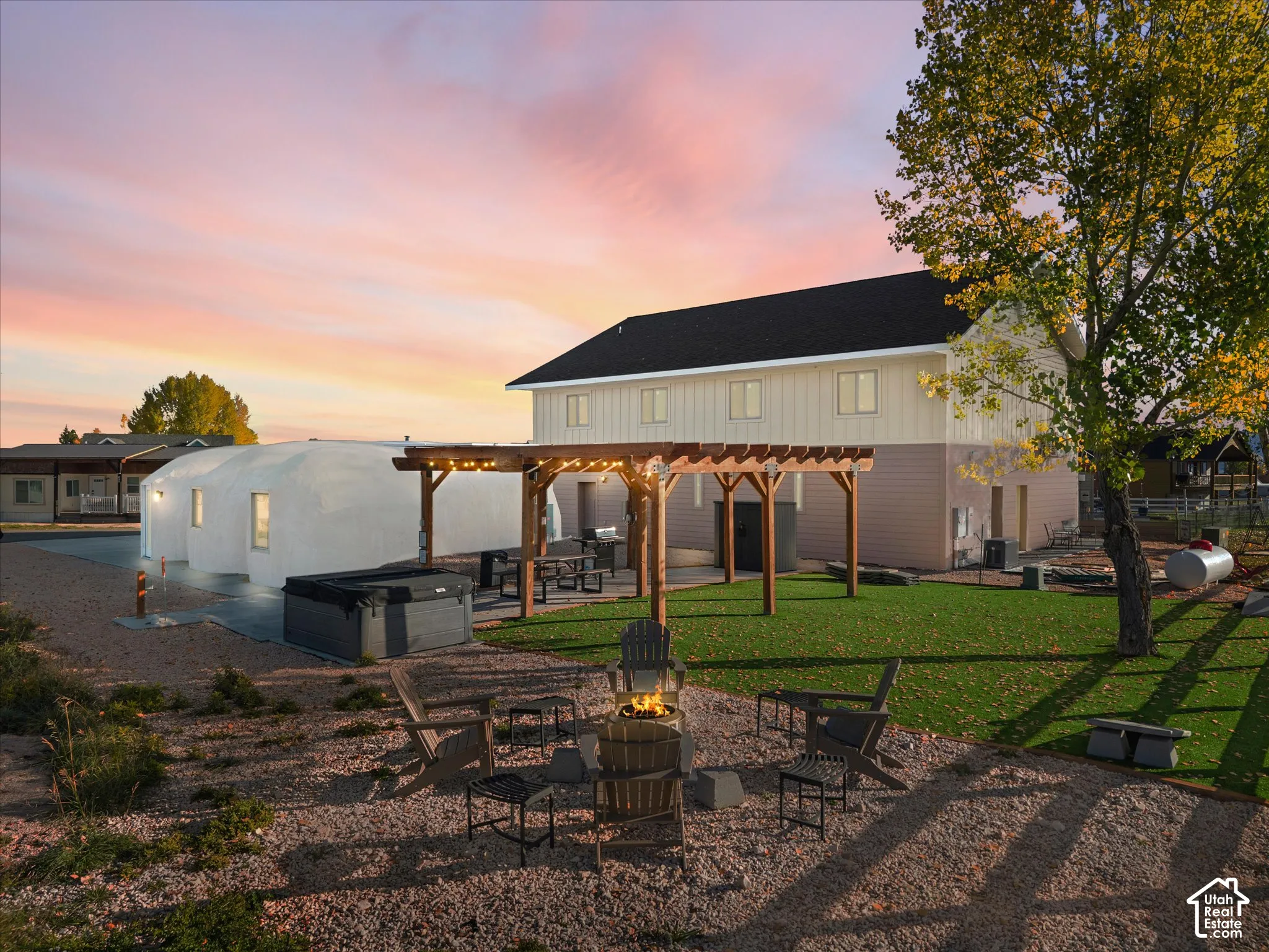 Outdoor space featuring a gravel fire pit area, wooden pergola, artificial turf, and hot tub
