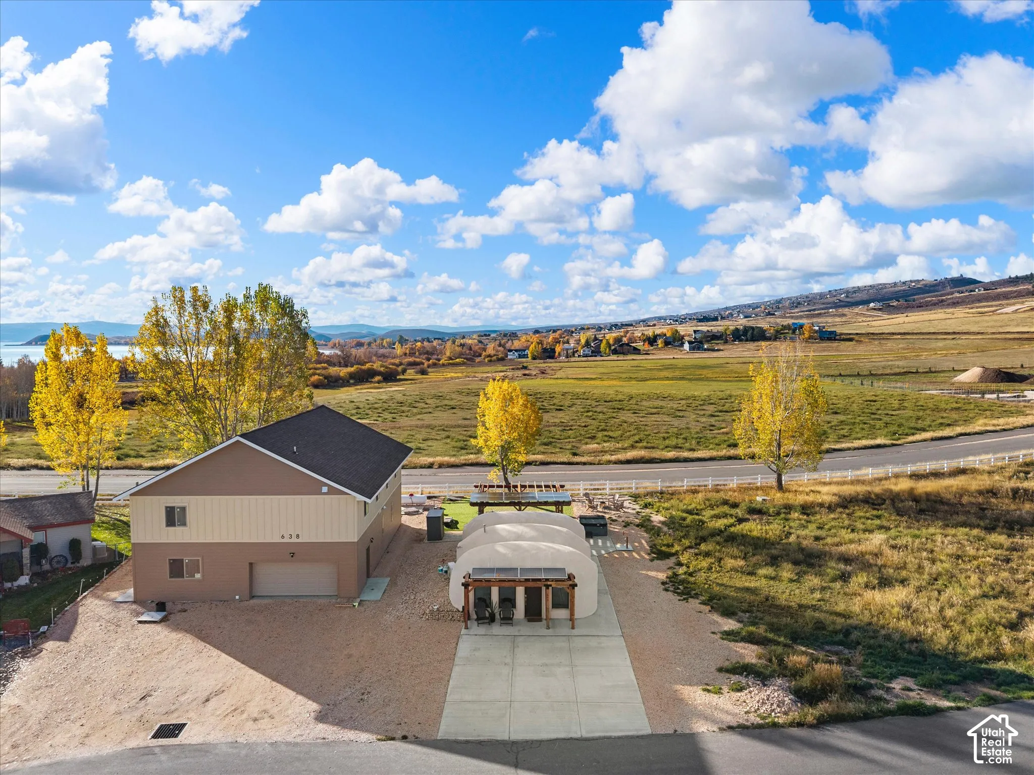 Two-story residence featuring vertical and horizontal siding, a concrete driveway, two attached pergola structures, and a multi-car garage