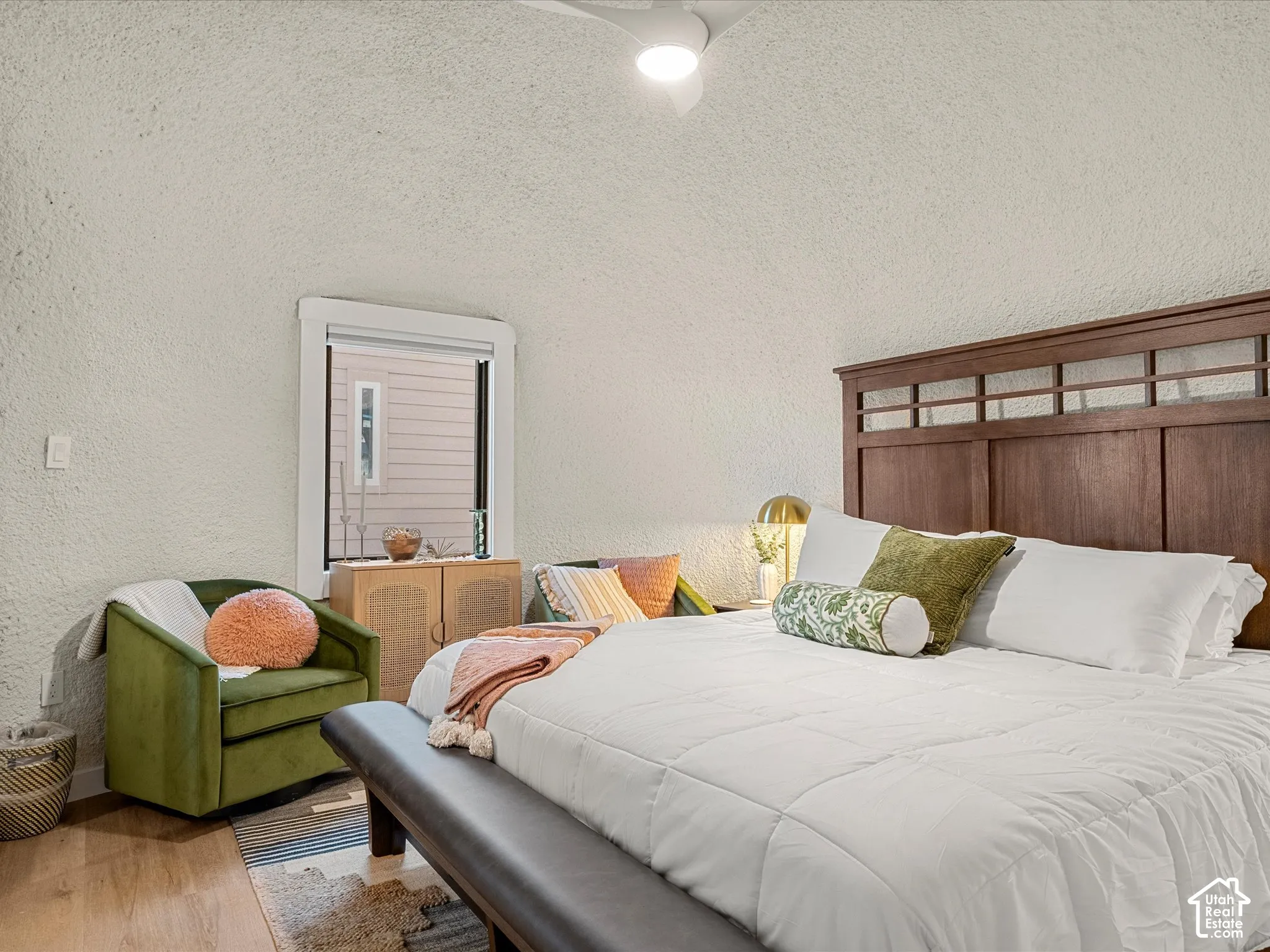 Room featuring a vaulted textured ceiling, integrated ceiling fan with light fixture, and wood-finish flooring