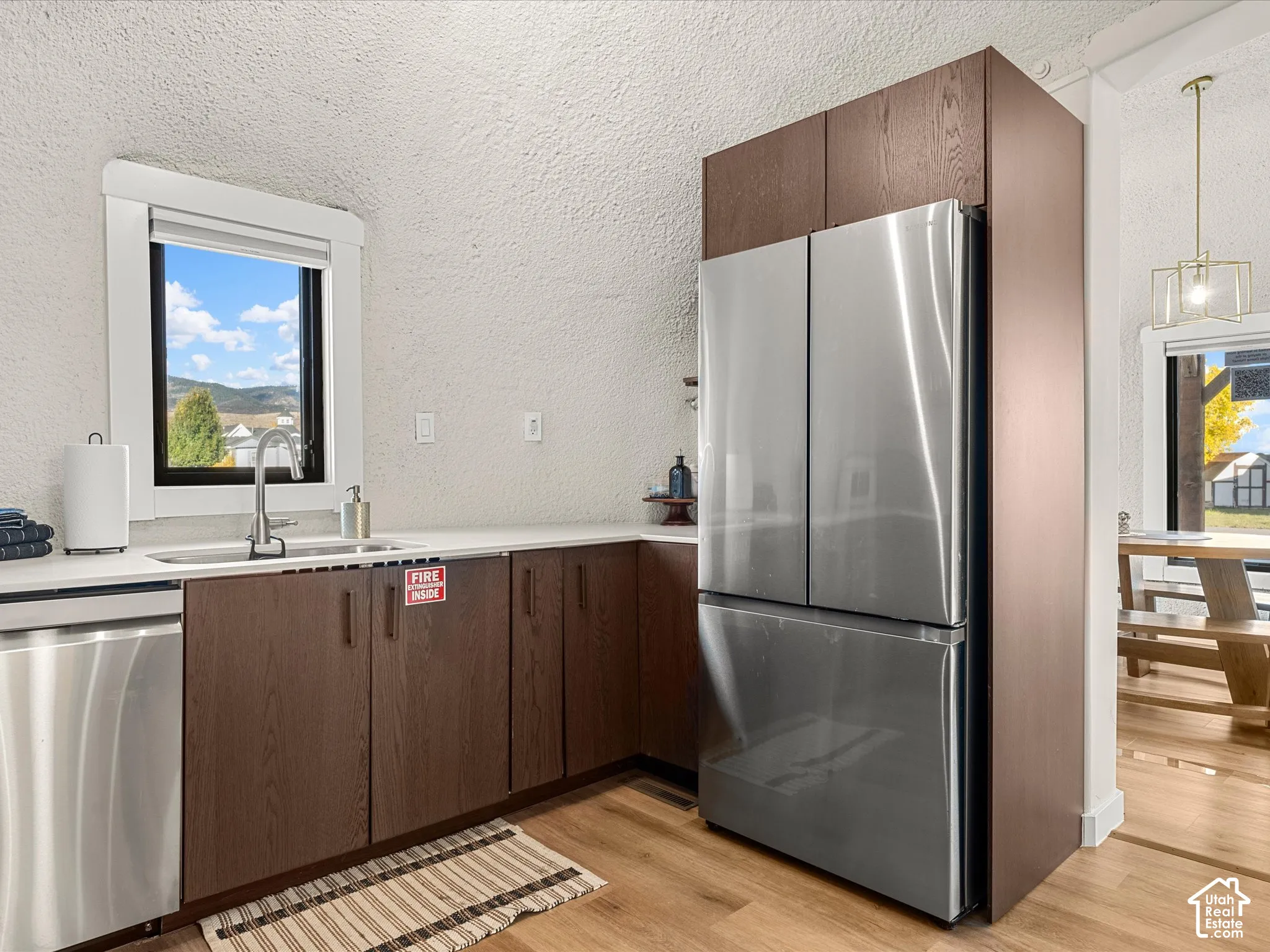 Kitchen featuring dark wood-finish cabinetry, stainless steel appliances, a stainless steel undermount sink, and wood-finish flooring