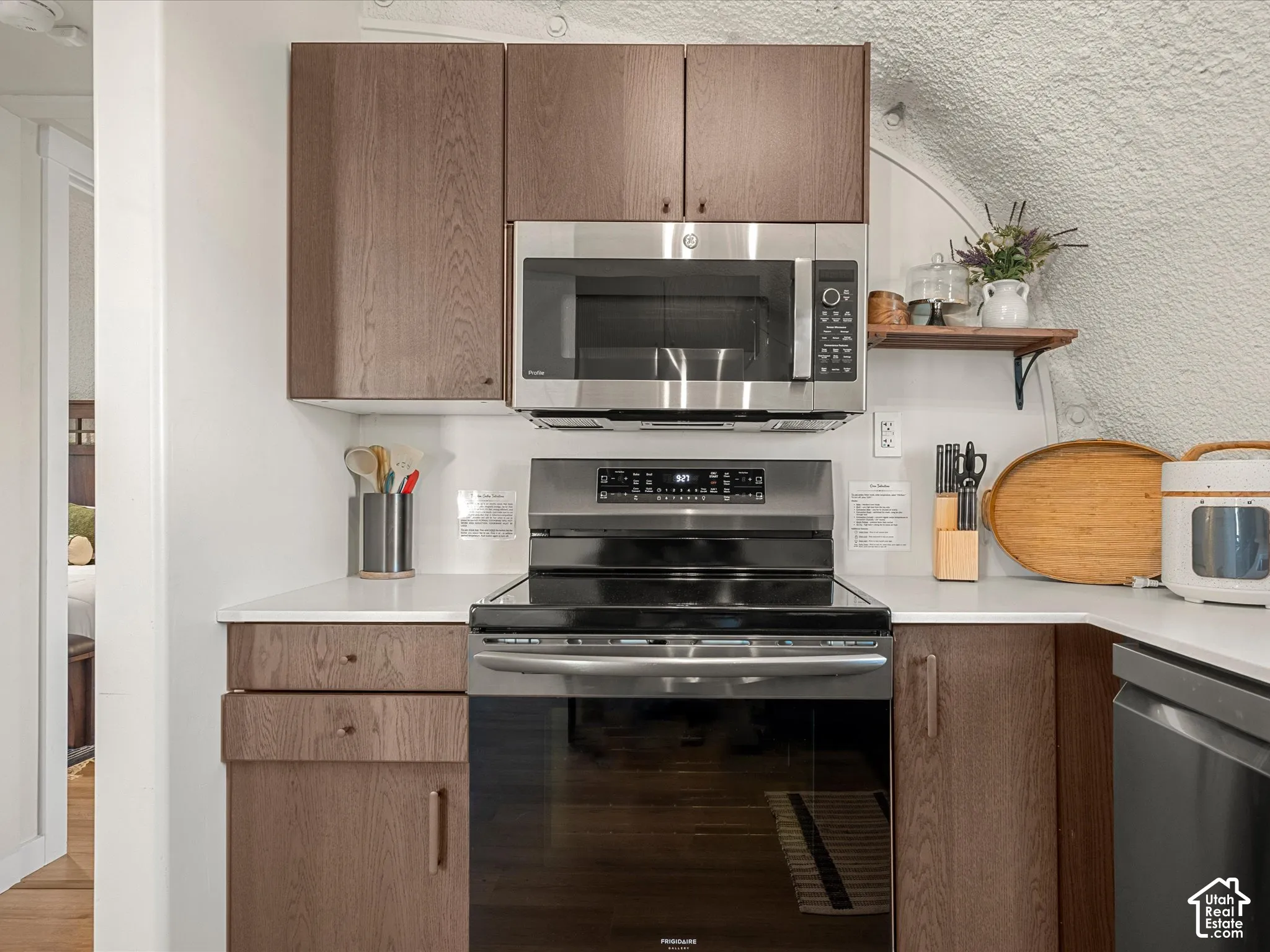 Kitchen featuring wood-finish cabinetry, solid surface countertops, a stainless steel over-the-range microwave, and a stainless steel freestanding electric range