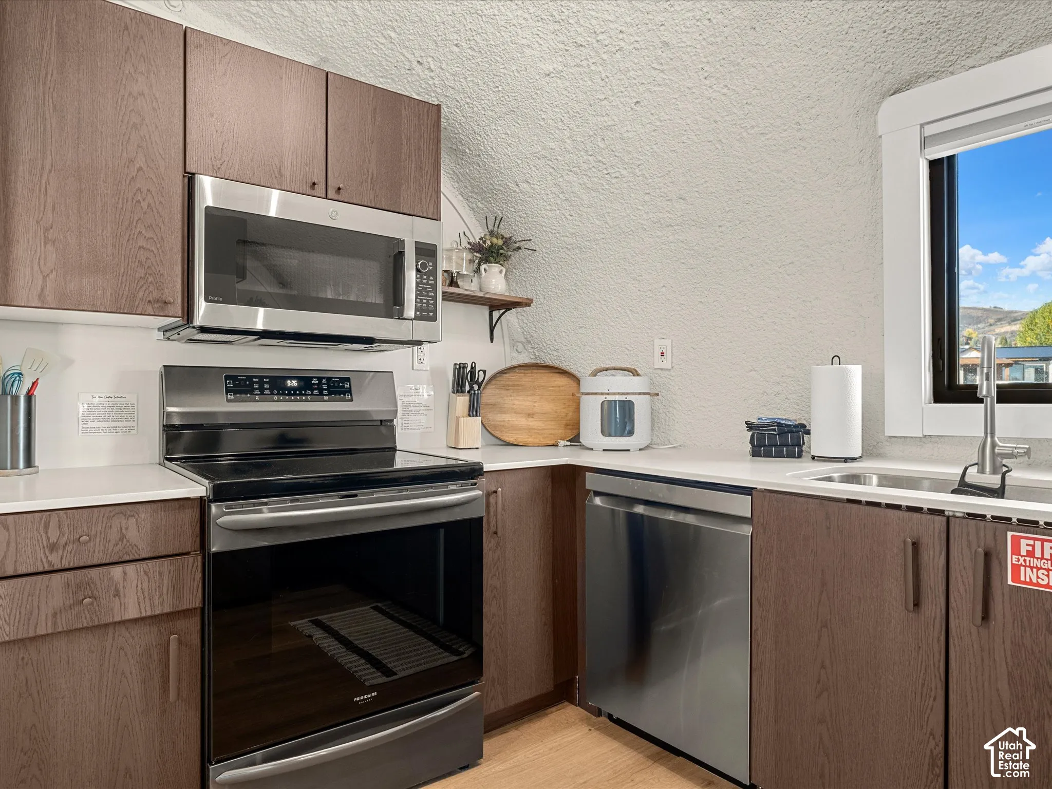 Kitchen featuring stained wood-finish cabinetry, white solid-surface countertops, and a stainless steel appliance package