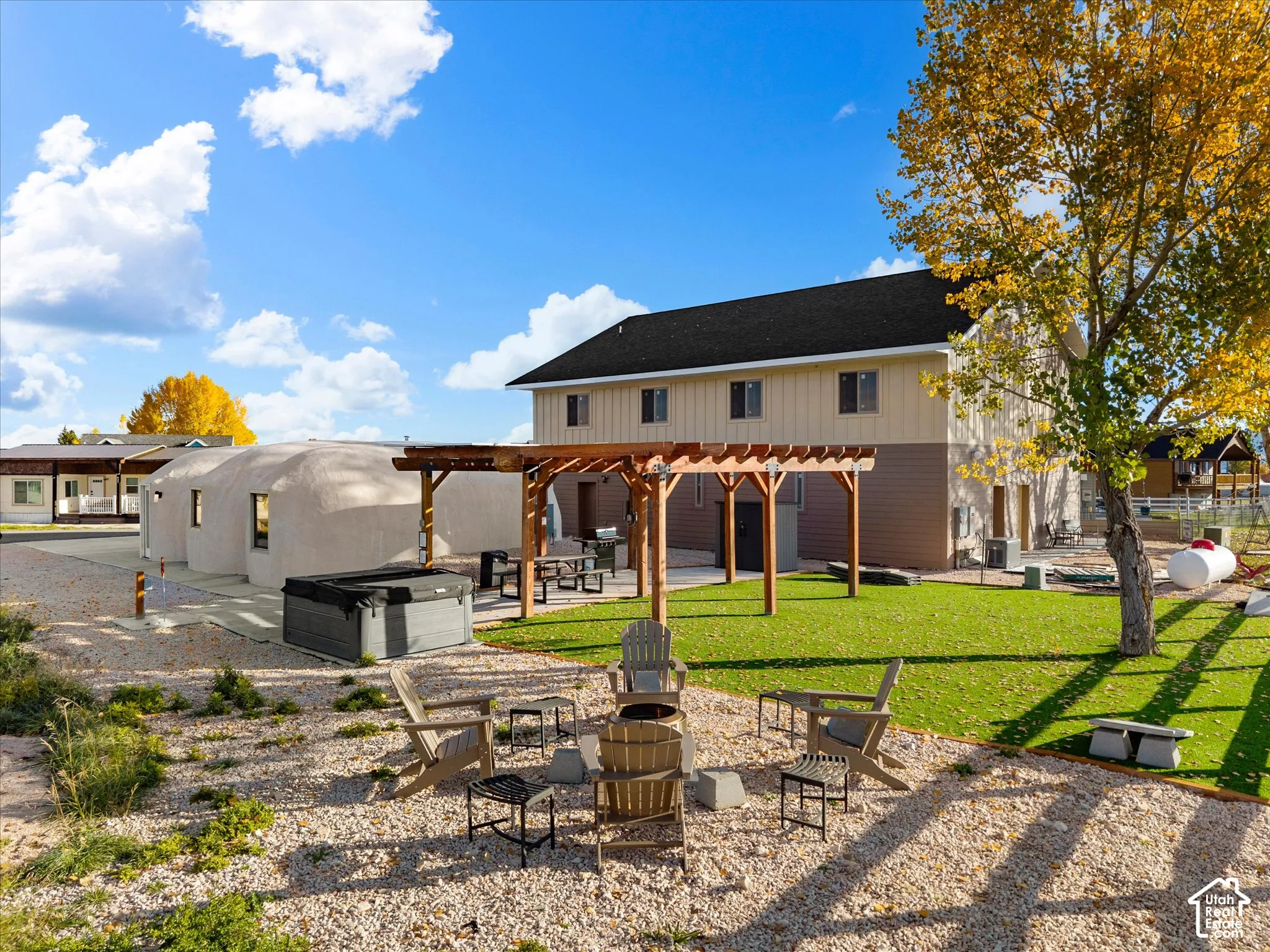 Expansive grounds featuring a wooden pergola, manicured synthetic lawn, graveled landscaping, built-in hot tub, and a dome-style outbuilding