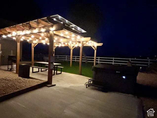 Custom wood pergola with integrated solar panels, concrete patio, and white rail fencing