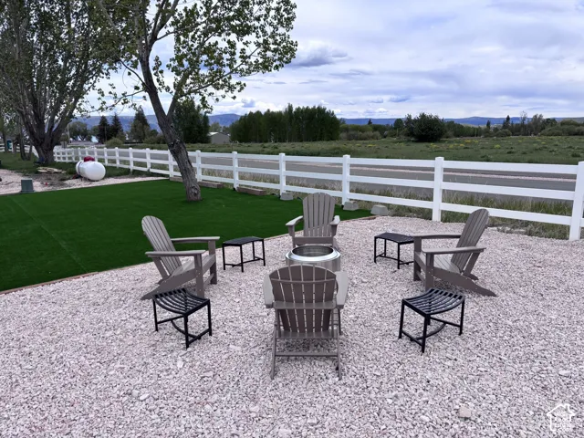Outdoor living area featuring gravel hardscaping, artificial turf lawn, and a perimeter white rail fence
