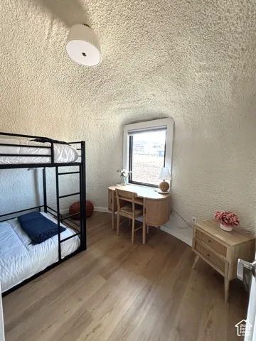 Arched room featuring textured plaster walls, wood-finish flooring, and a flush-mount light fixture